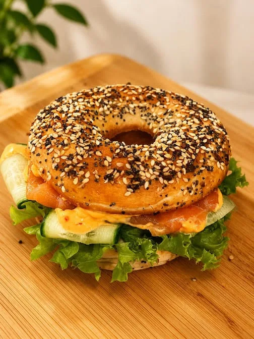 Loaded bagel sandwich stacked with deli meats and fresh vegetables at Maison Croissant & Bowls Winnipeg